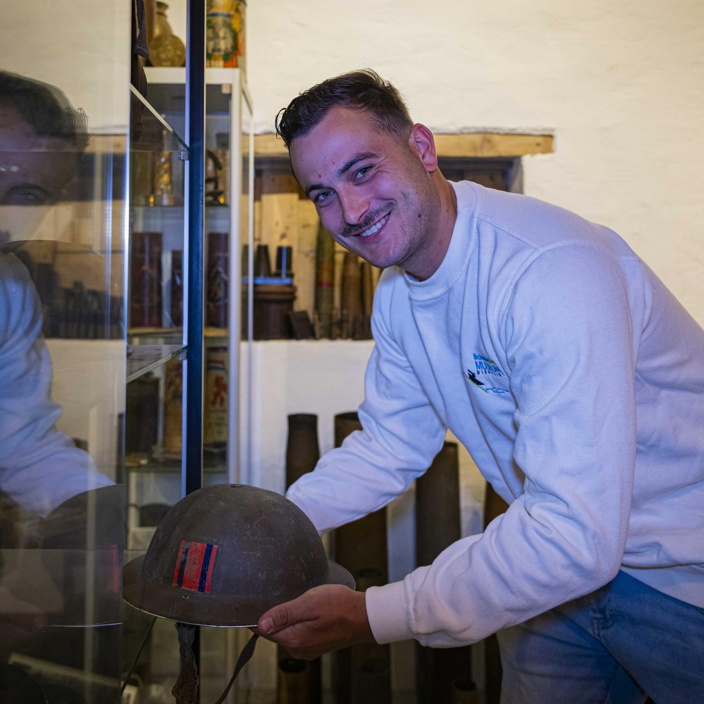 Rik houdt een helm uit de Tweede Wereldoorlog vast van een soldaat.