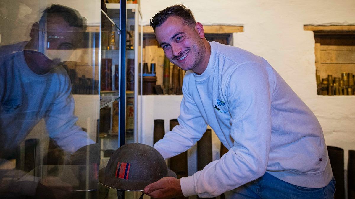 Rik houdt een helm uit de Tweede Wereldoorlog vast van een soldaat.