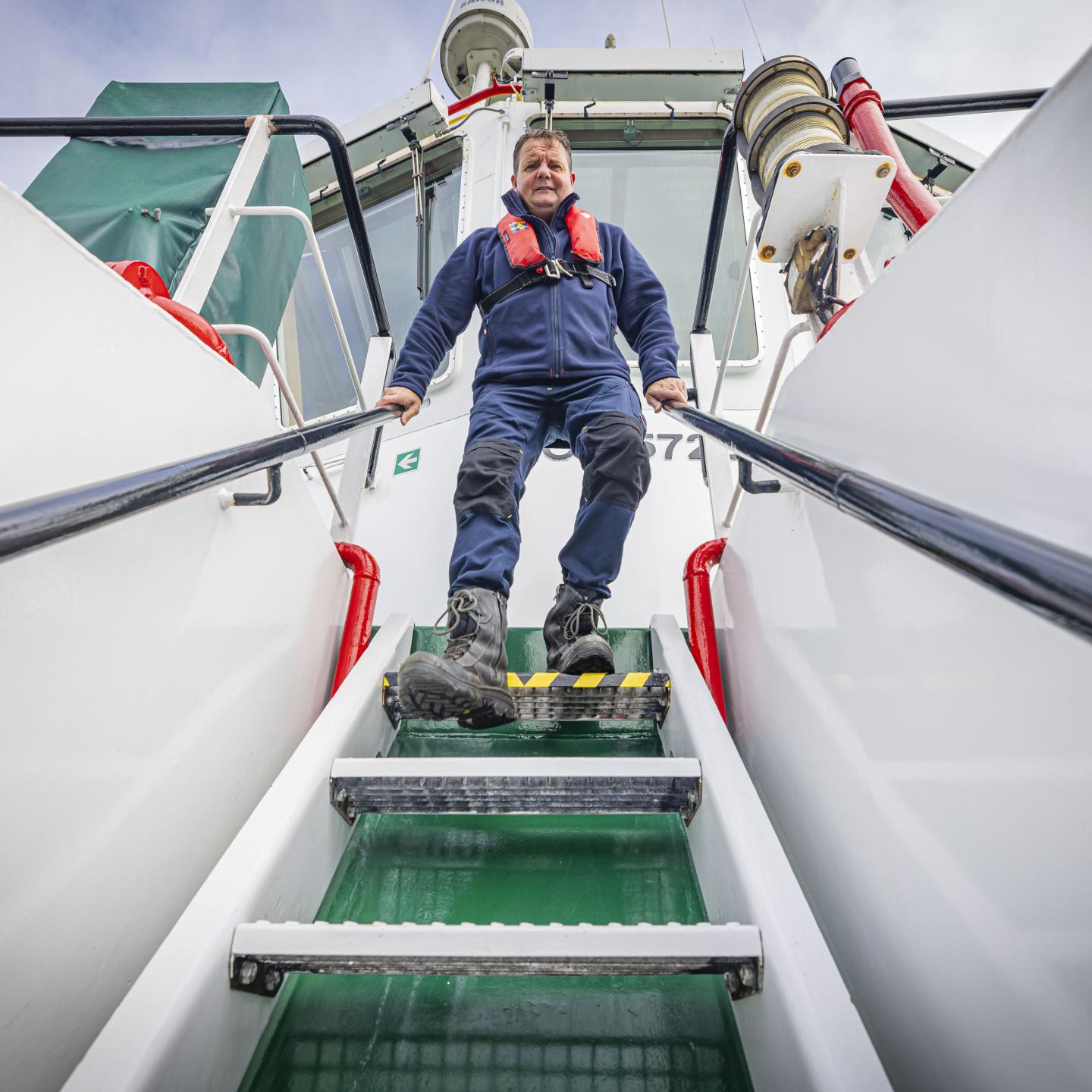 Schipper Bertus stapt de metalen trap af van de stuurhut naar het dek