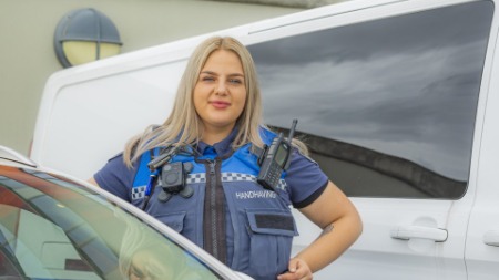 Kristien als boa tussen geparkeerde auto's