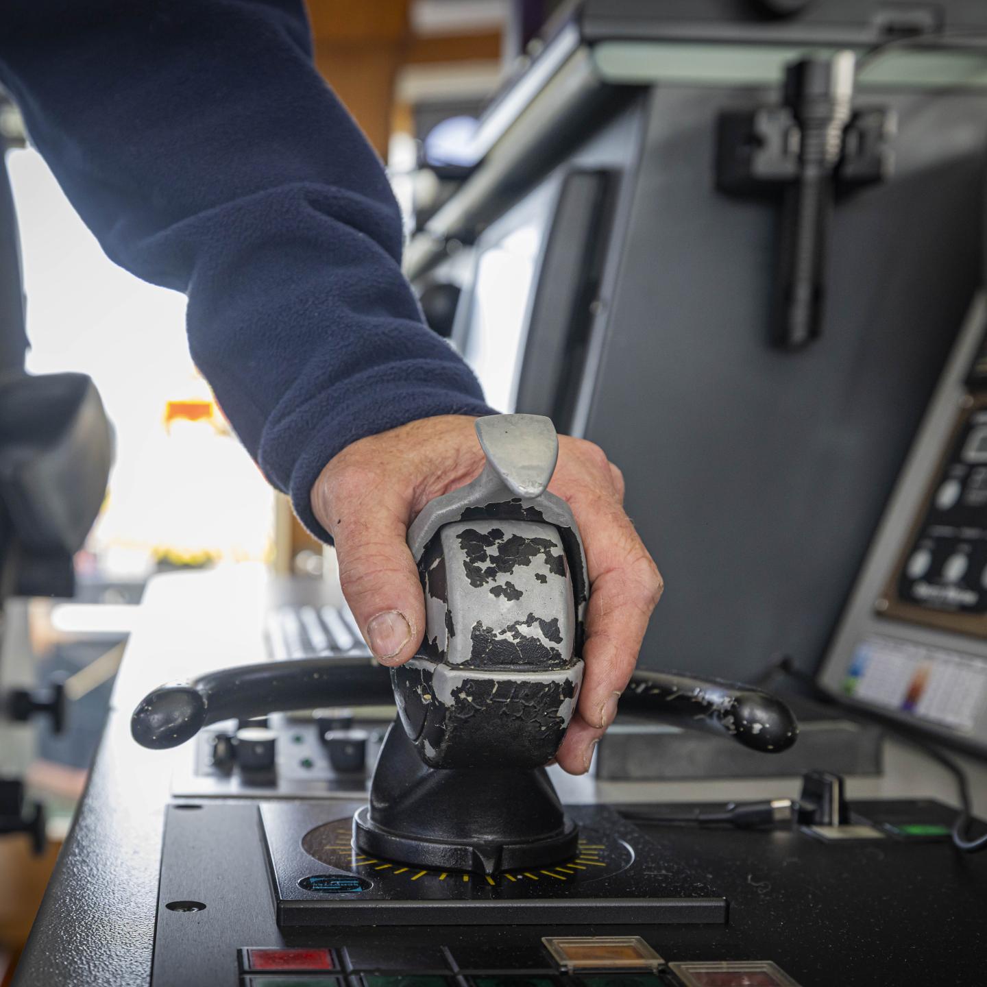De hand van kapitein Bertus ligt op een besturingshendel in het schip
