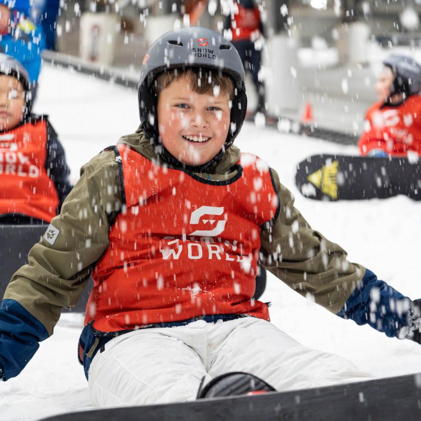 Jongetje zit op de piste van SnowWorld Terneuzen tijdens een snowboardles