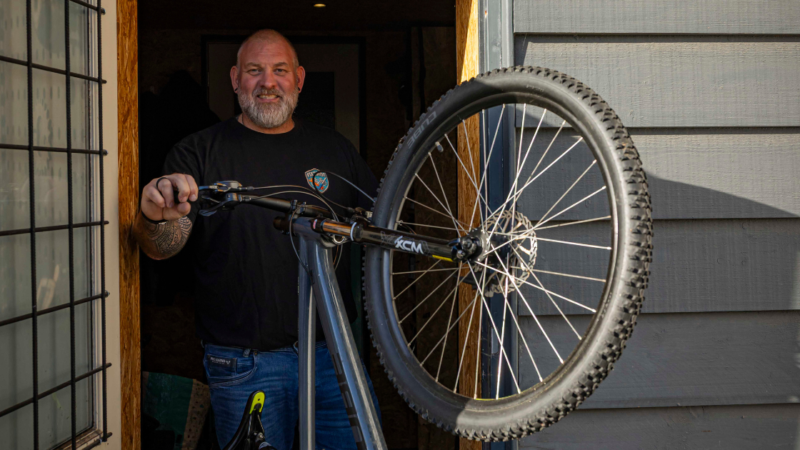 Robert in de deuropening van zijn werkplaats met een fiets in zijn hand