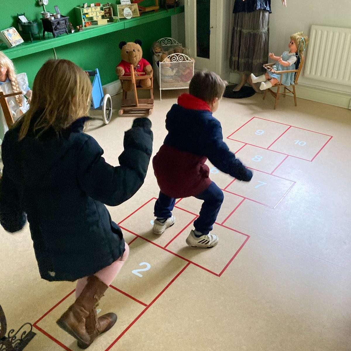Jong meisje en jong jongetje spelen hinkelen in het museum
