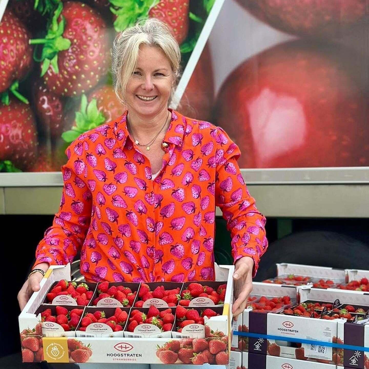 Vrouw met aardbeienshirt aan poseert met kistje aardbeien in de handen