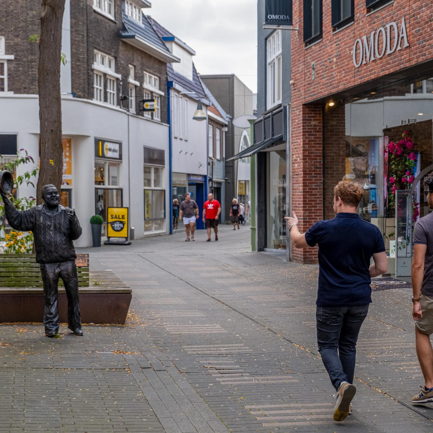Winkelstraat in Terneuzen met modewinkel Omoda rechts en links het standbeeld van Frank Koulen
