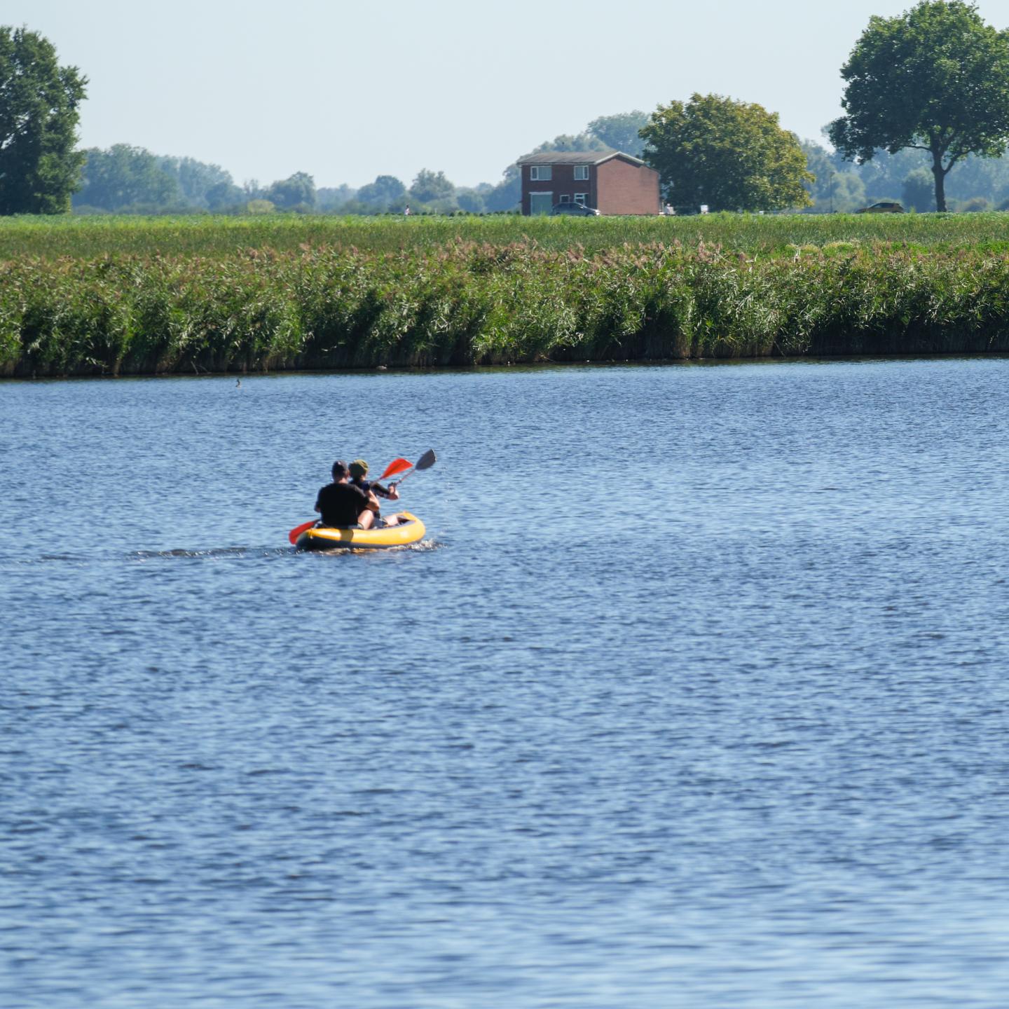 Twee mensen in één kano op een kreek in de omgeving Terneuzen, omringd door polderlandschap