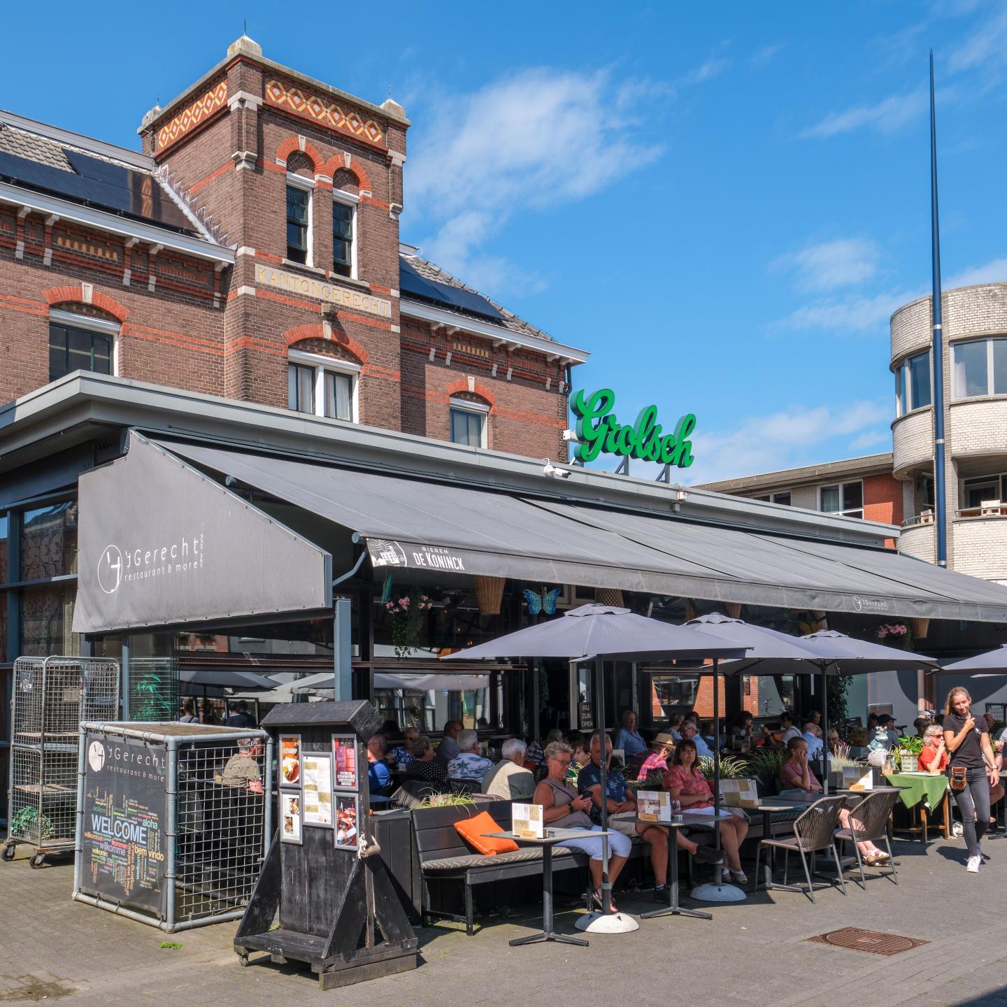 Zonnig terras vol mensen genietend van het weer en het lekkere eten en drinken