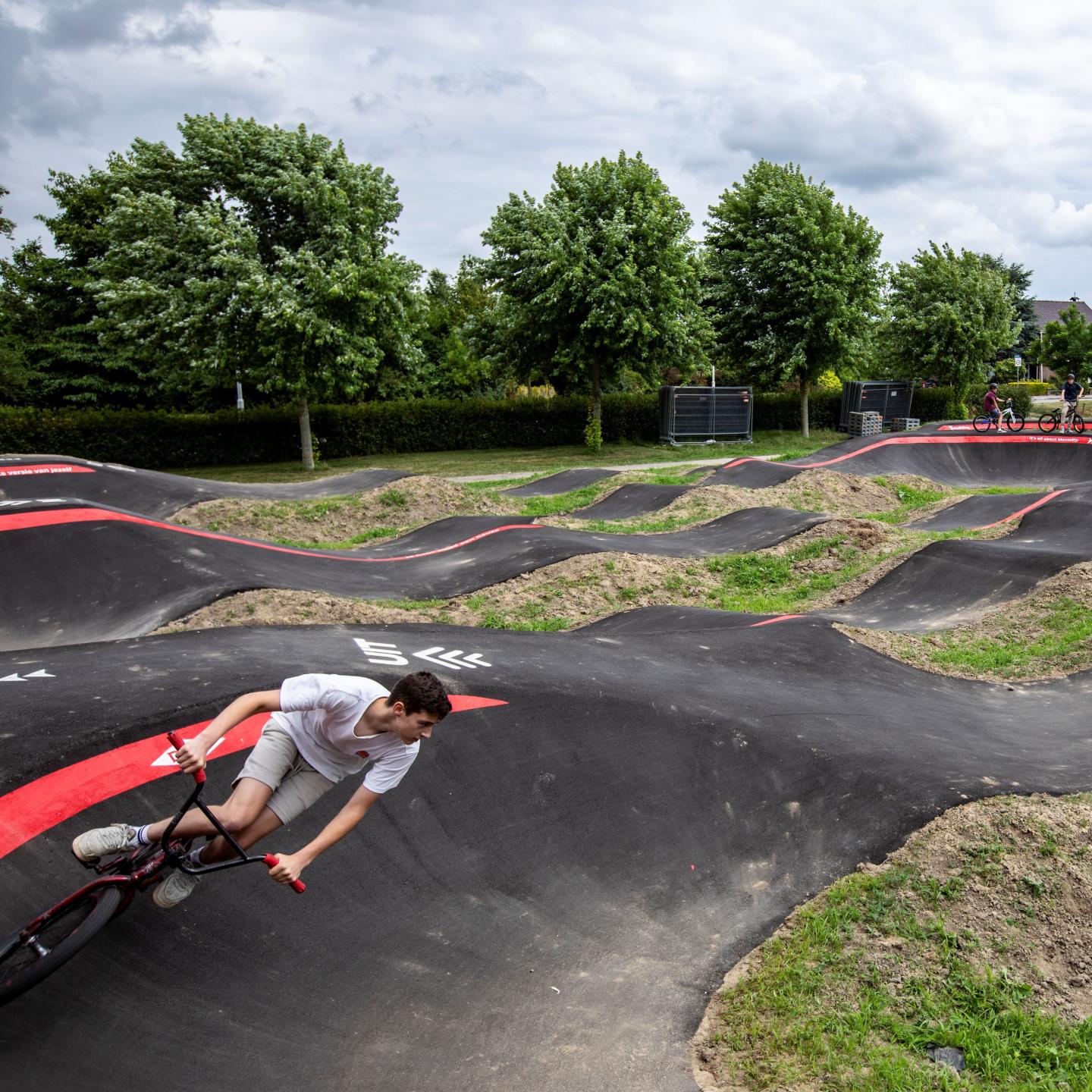BMX'er rijdt door kombocht op pumptrackbaan Axel