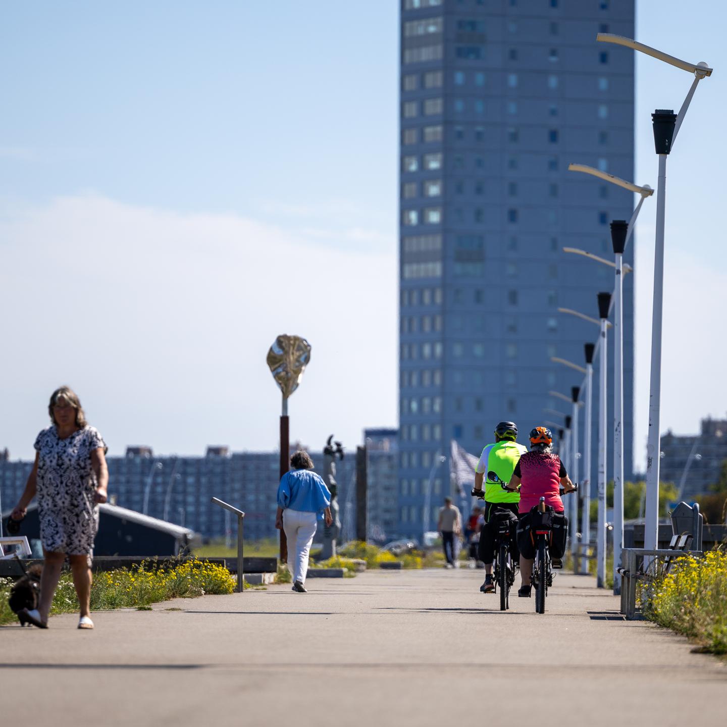 Mensen fietsen en wandelen op de Scheldeboulevard in Terneuzen met op de achtergrond een groot appartementengebouw