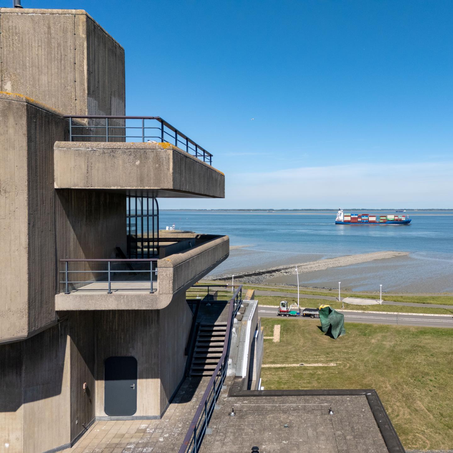 Detailfoto 'stuurhut' van het stadhuis met op de achtergrond de Westerschelde met zeeschip