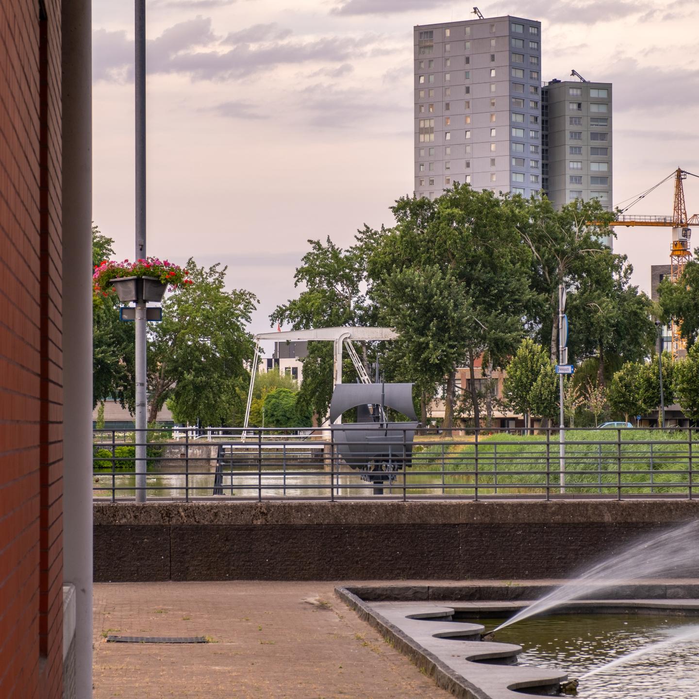 Kunstwerk van de Vliegende Hollander bekeken door de poort van een tegenoverliggend kantorencomplex