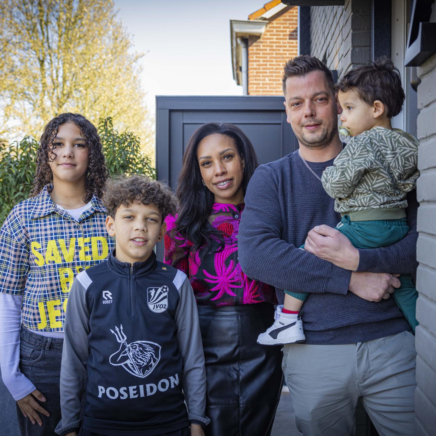 Suwingel poseert met haar man en drie kinderen bij de voordeur van hun woning