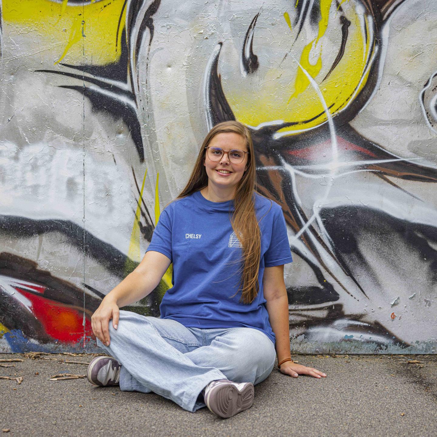 Chelsy zit voor graffitimuur