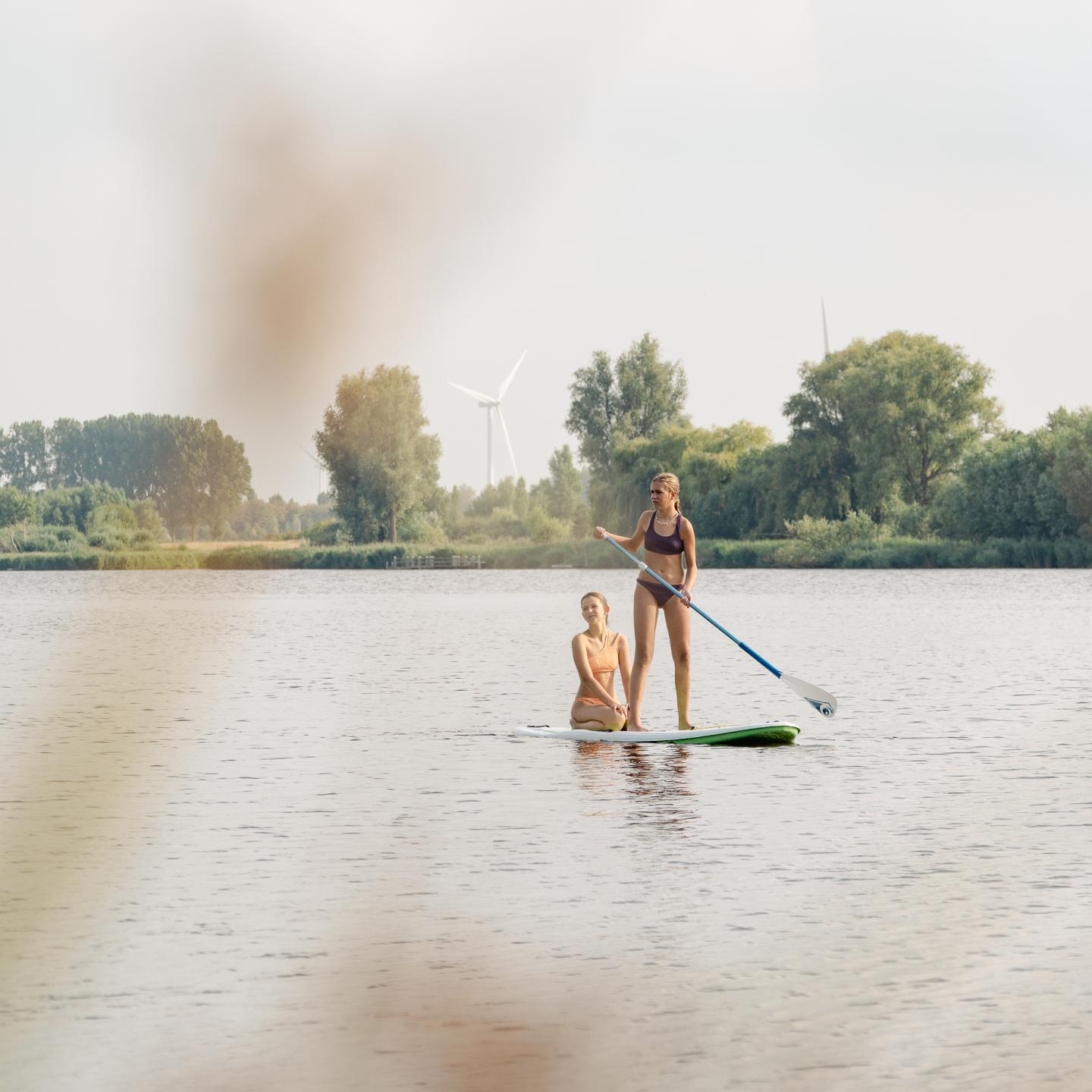 Kinderen op een sup op de kreek met de skyline van Terneuzen erachter